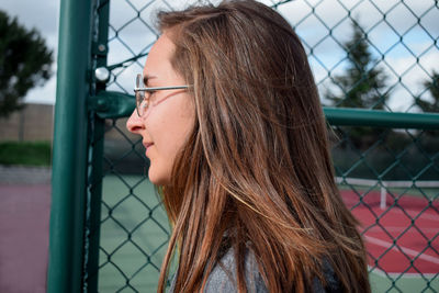 Portrait of a young woman looking through fence
