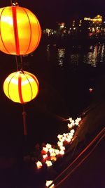 Illuminated lanterns hanging in city against sky at night