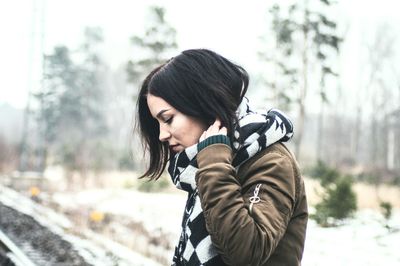 Young woman standing in snow against trees