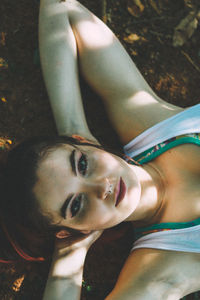 Close-up portrait of young woman lying down outdoors