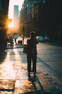 Rear view of man standing on sidewalk in city
