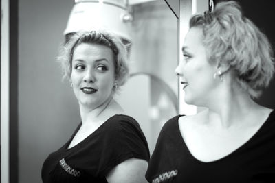 Smiling woman standing in front of mirror at salon