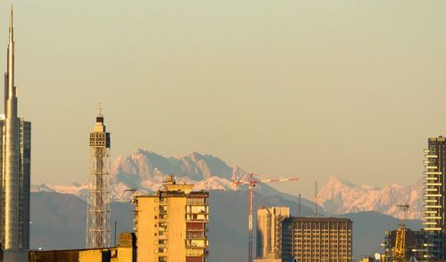 Buildings by mountains against clear sky