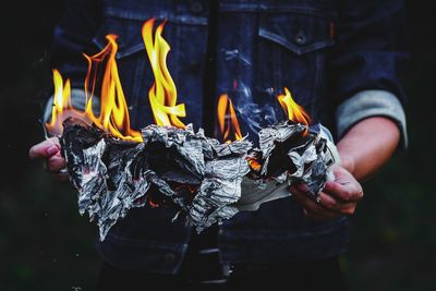 Midsection of man holding burning paper