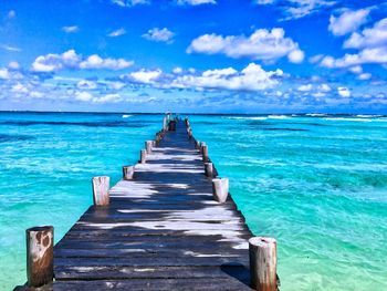 Wooden pier on sea against sky