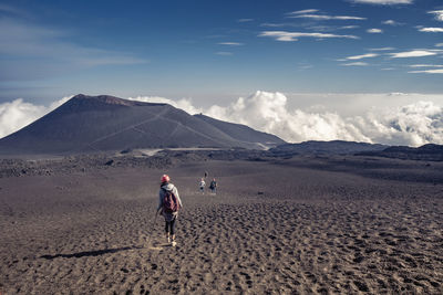 Rear view of men walking on land against sky