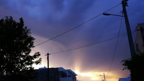 Low angle view of silhouette electricity pylon against sky