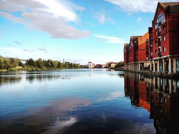 Buildings by lake against sky in city