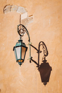 Lamp with a shadow on the orange old wall in italy