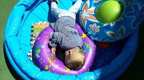 High angle view of boy relaxing with inflatable ring in wading pool on sunny day