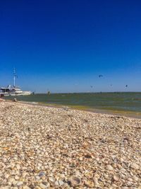 Surface level of beach against clear blue sky