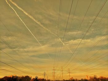 Low angle view of electricity pylons and sky during sunset 