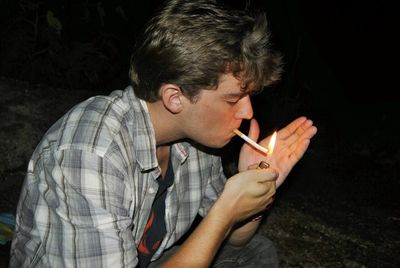 Young man burning cigarette at night