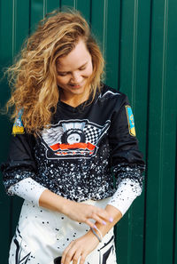 Young woman with curly hair in protective gear for motocross smiling