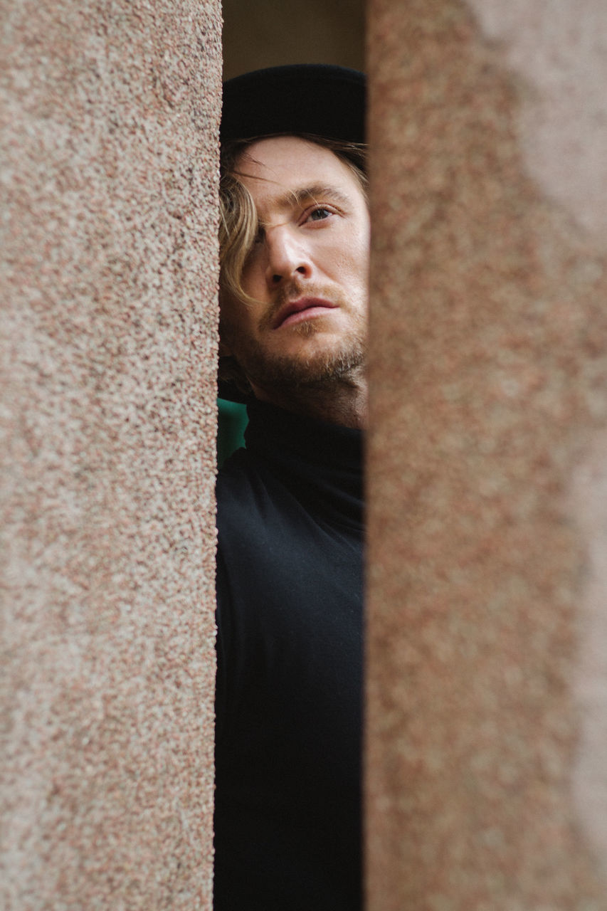 one person, portrait, real people, beard, young men, young adult, looking at camera, looking, front view, lifestyles, mid adult, facial hair, leisure activity, low angle view, men, casual clothing, headshot, contemplation, architectural column, human face