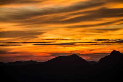 Scenic view of silhouette mountains against orange sky