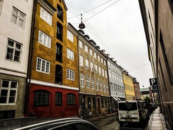 Cars on road by buildings in city against sky