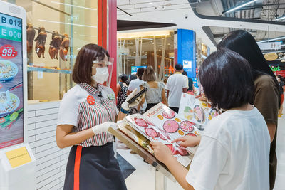 Rear view of people standing at store