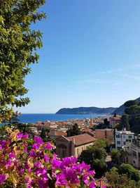 View of town by sea against clear blue sky