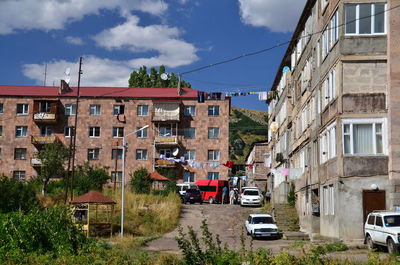 Cars on road by buildings in city against sky