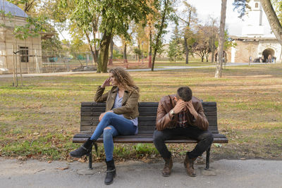 Angry couple sitting on bench at park