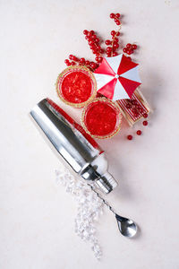 High angle view of red berries on table against white background