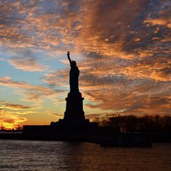 Silhouette of statue against cloudy sky during sunset