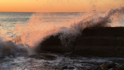 Close-up of waves splashing on shore during sunset