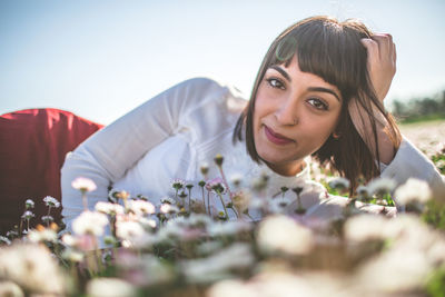 Portrait of happy young woman relaxing on flowers field