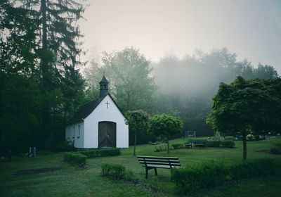 Park bench by building against sky