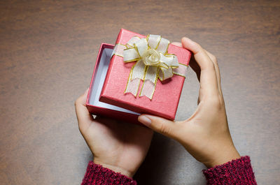 Cropped hands of woman holding gift box on table