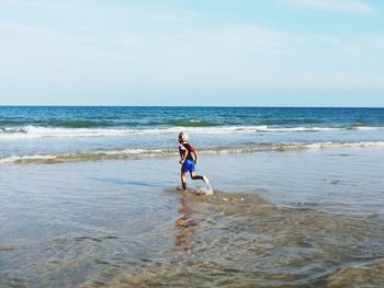 Boy running towards sea at beach