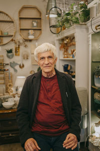 Portrait of senior male owner sitting at home decor store