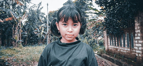 Portrait of boy standing against trees