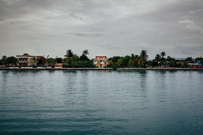 Buildings by lake against sky