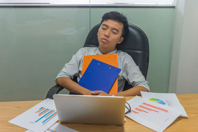 Mid adult man using mobile phone while sitting on table