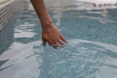 Cropped hand of woman in swimming pool