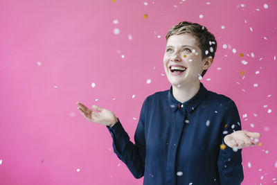 Young man looking away while standing against pink background