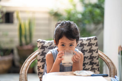 Cute little girl drinking milk at table