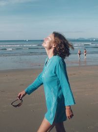 Woman standing on beach against sea against sky