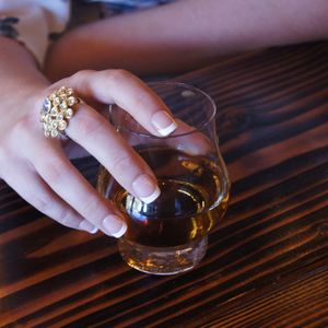 Close-up of woman drinking glass on table