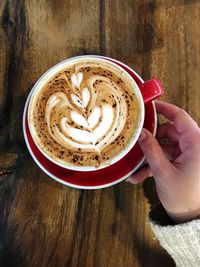 Close-up of hand holding coffee cup on table