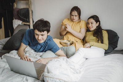 Siblings watching movie on laptop with down syndrome sister at home