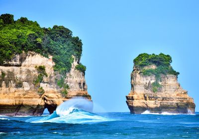Rock formations in sea against clear blue sky