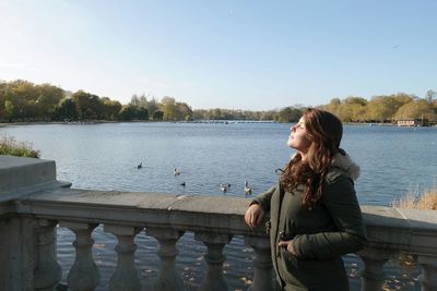 Woman sitting on lake against clear sky