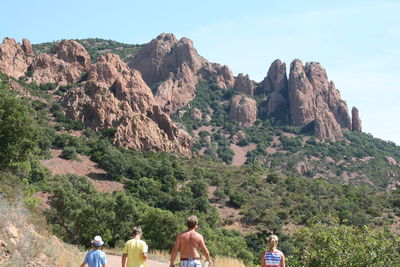 Rear view of people walking on mountain against sky