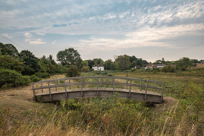 Footbridge over field against sky