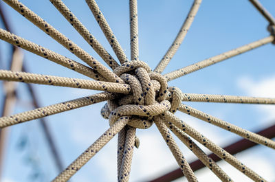 Close-up of rope tied to bollard against sky