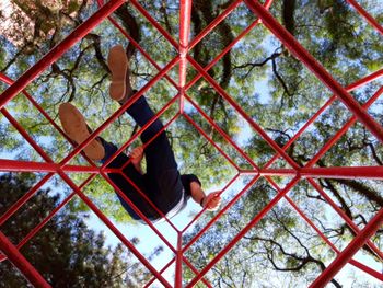 Low angle view of man on metallic structure at park