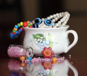 Close-up of bracelets in cup by beads on table